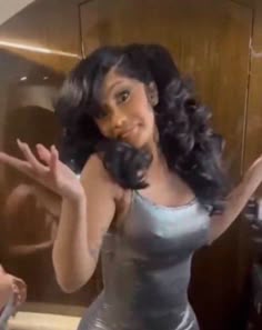 a woman in a silver dress holding her hands out to the side while standing next to a mirror