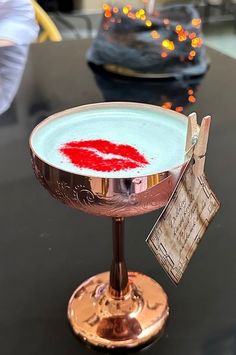 a blue and white drink with a red lips on it's rim sitting on a table
