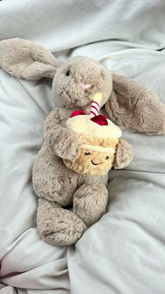 a stuffed rabbit with a birthday cake on it's back sitting on a bed