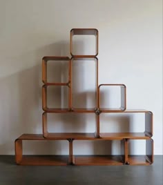 a book shelf made out of wooden shelves on top of a floor next to a wall