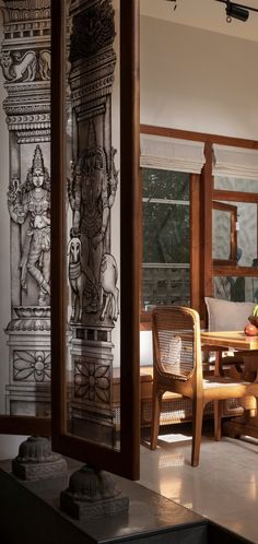 a living room with a table and chairs in front of a large painting on the wall