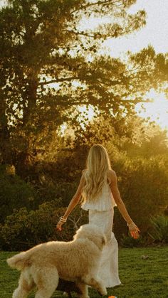 a woman in white dress playing with two dogs
