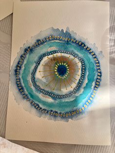 an abstract painting on white paper with blue and yellow circles in the center, surrounded by other art supplies