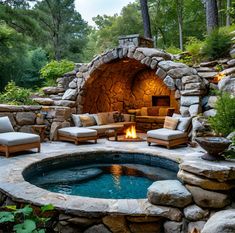 an outdoor hot tub surrounded by stone walls and seating area with fire pit in the middle