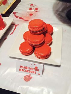 red macaroons sitting on a white plate next to a sign that says miami metro macaroons