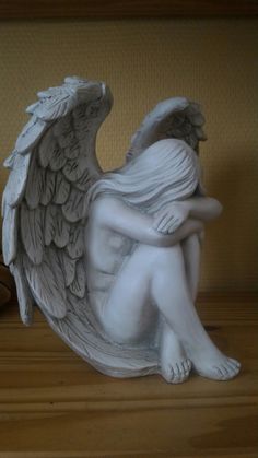 an angel statue sitting on top of a wooden table