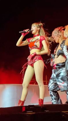 two women are performing on stage with microphones