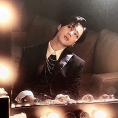 a man sitting on a couch in front of a mirror with light bulbs around him