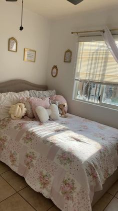 a bedroom with a bed, window and stuffed animals on the pillowcase in front of it