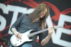 a man with long hair playing an electric guitar