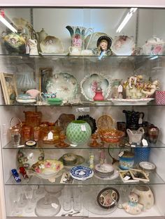 a display case filled with lots of glassware and figurines on top of shelves