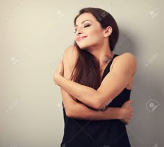 a beautiful woman with long hair posing for the camera in front of a gray wall
