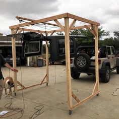 a man standing next to a wooden structure with a dog in it's mouth