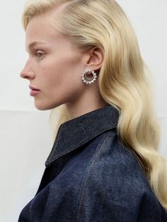 a woman with long blonde hair and earrings on her head, looking off to the side