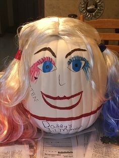 a paper mache pumpkin decorated to look like a clown with pink hair and blue eyes