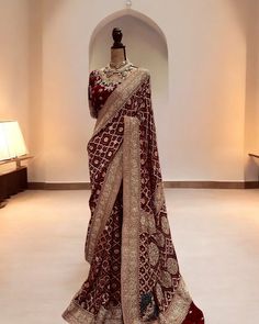 a mannequin dressed in a red and gold sari with an intricate pattern