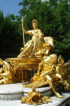 a golden statue sitting in the middle of a park