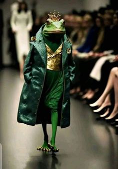 a frog dressed in green and gold is walking down the runway