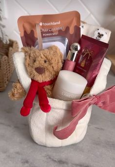 a teddy bear sitting in a white basket filled with cosmetics and personal care items,