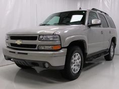 a silver chevrolet suburban truck parked in a white room with a black and white checkered floor