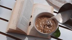 an open book on a table with a cup of coffee and spoon in front of it