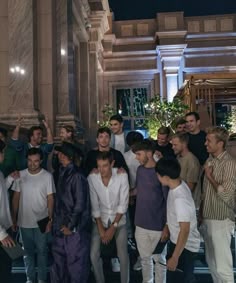 a group of young men standing next to each other in front of a building at night