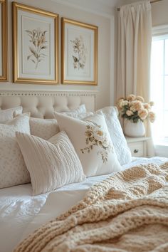 a bed with white sheets and pillows in front of two framed pictures on the wall