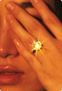 a close up of a person holding their hands to her face with a ring on it