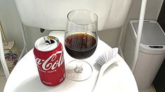 a glass of coke next to a can of soda on a table in an airplane