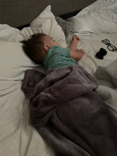 a small child laying on top of a bed under a blanket