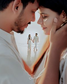 a man and woman standing next to each other in front of the ocean holding hands