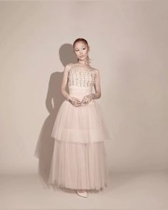 a woman in a pink dress standing against a wall