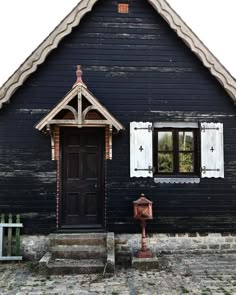 a black house with white shutters and a red fire hydrant