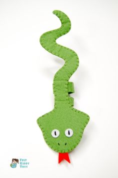 a green snake with a red ribbon on it's neck is hanging from a hook