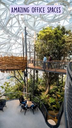 people are sitting at tables in the middle of an indoor area with trees and plants