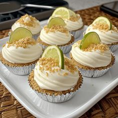 several cupcakes on a white plate with lime slices and crumbs around them