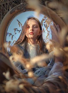 a woman is looking at herself in the mirror while sitting down and holding her hand up to her face