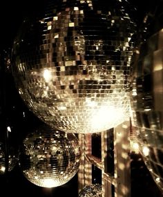 shiny disco balls hanging from the ceiling in front of a mirror ball sculpture at night