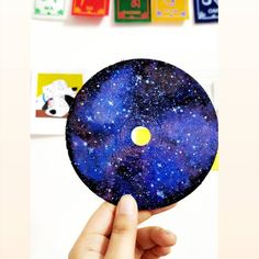 a person holding up a blue disc with stars on it in front of colorful magnets
