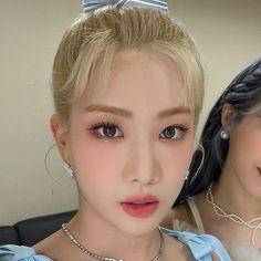 two young women wearing necklaces and pearls, one with blue eyes the other has blonde hair