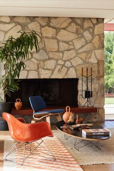 a living room filled with furniture and a fire place next to a stone fireplace covered in potted plants