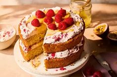 a cake with raspberries on top is sitting on a table next to other desserts