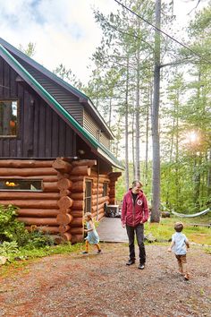a woman and two children standing in front of a log cabin