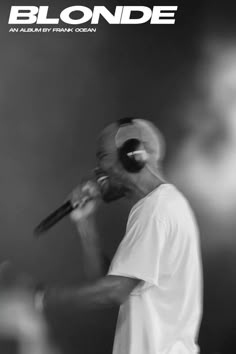 a man holding a microphone in front of his face and wearing headphones on stage