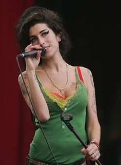 a woman holding a microphone in her right hand and singing into the microphone with both hands