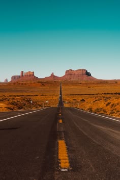 an empty road in the middle of desert with mountains in the backgrouund