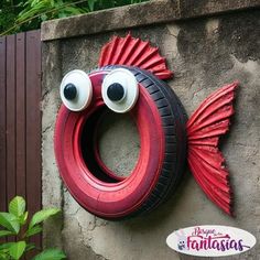 a red tire with googly eyes hanging on the side of a wall next to a sign