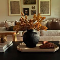 a black vase sitting on top of a table next to a white plate filled with food