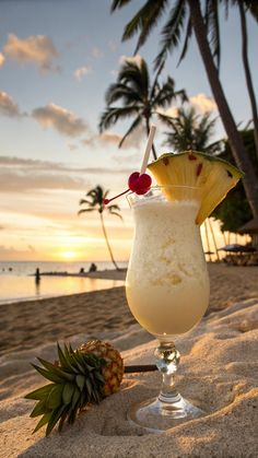 a drink on the beach with a pineapple next to it