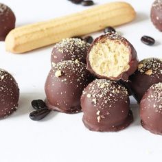 chocolate covered desserts are arranged on a white surface next to a rolling pin and cinnamon stick